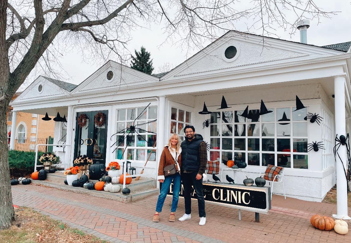 Dr. AJ and his fiancee outside Redwater Dental Clinic decorated for Halloween with witches' hats, spiders, and pumpkins